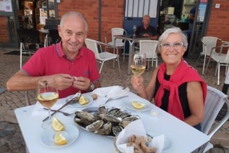 Photo of Gigi and Jean-Pierre, owners of Marina Gigi and Casa Gigi, eating oysters at the Olhão market. Holiday rental in Olhão in the south of Portugal